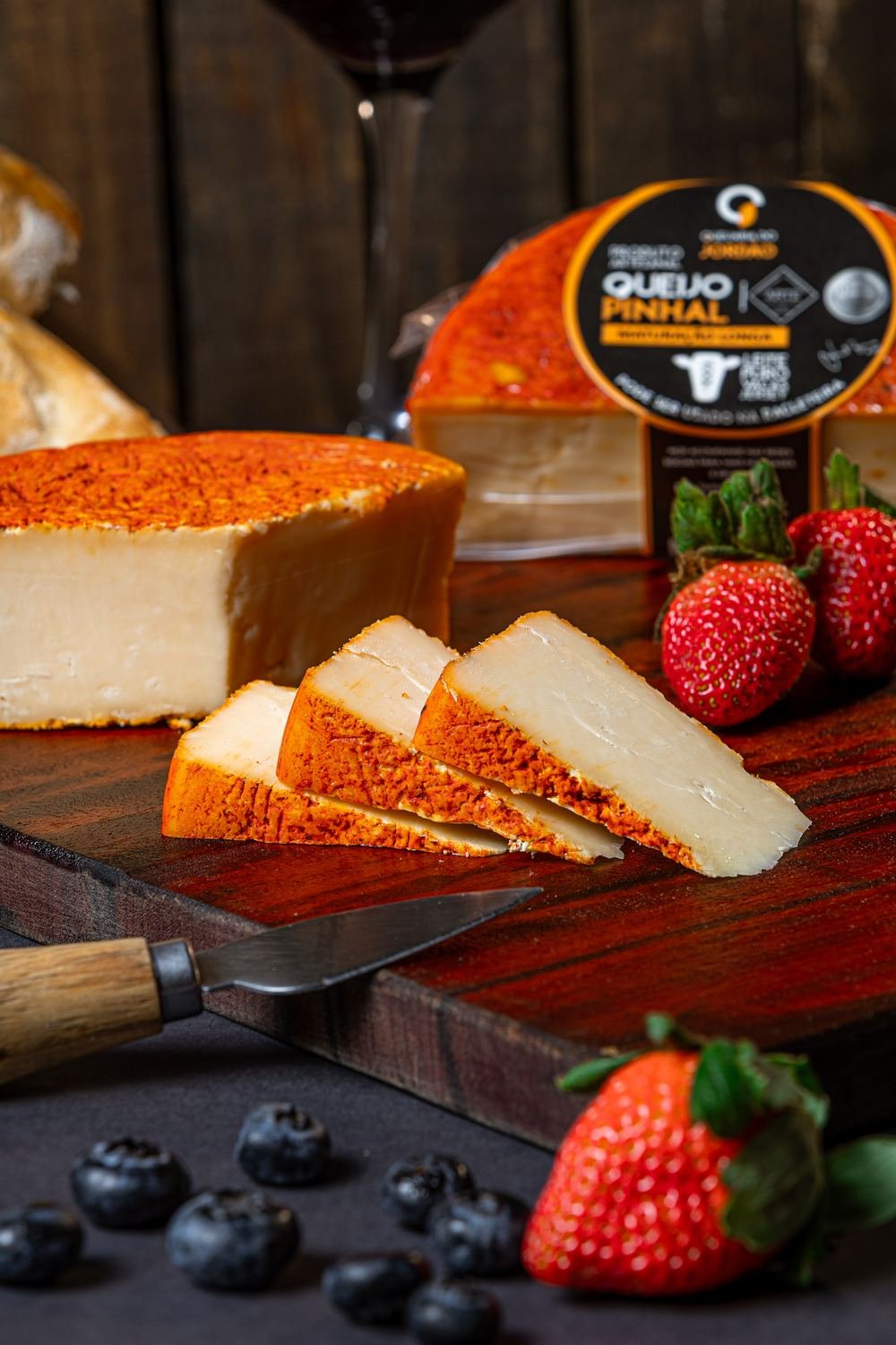 Queijo Pinhal Maturado cortado, mostrando a casca alaranjada e a massa firme