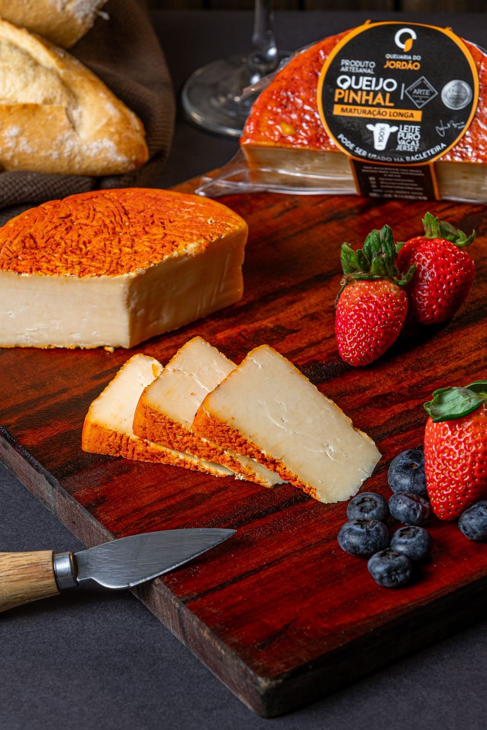 Fatias de Queijo Pinhal Maturado com casca alaranjada, servidas com morangos e mirtilos